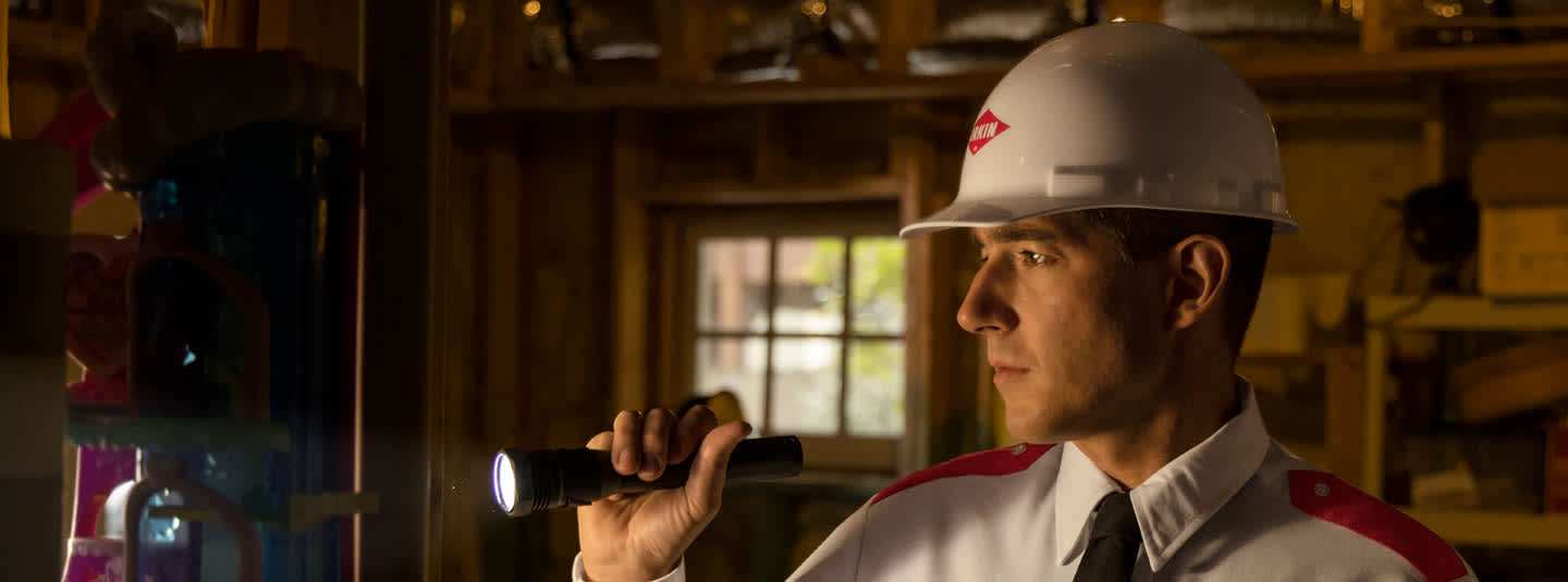 An Orkin Pro inspects a garage with a flashlight.